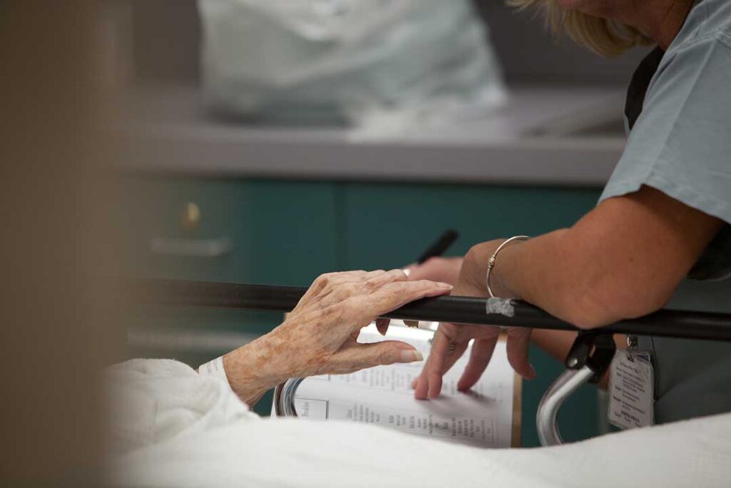 Adult child and older parent reviewing care notes together at a kitchen table.